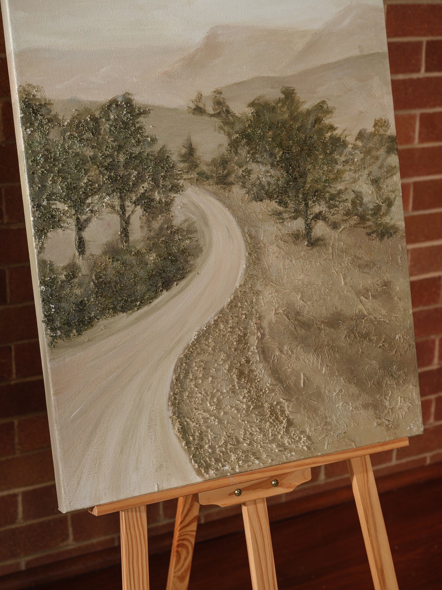 Abstract landscape painting titled Whispering Road, featuring a winding pale road through trees and hills in soft earthy tones