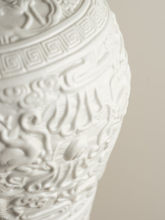 White porcelain meiping vase featuring intricate dragon relief motifs and geometric borders.
