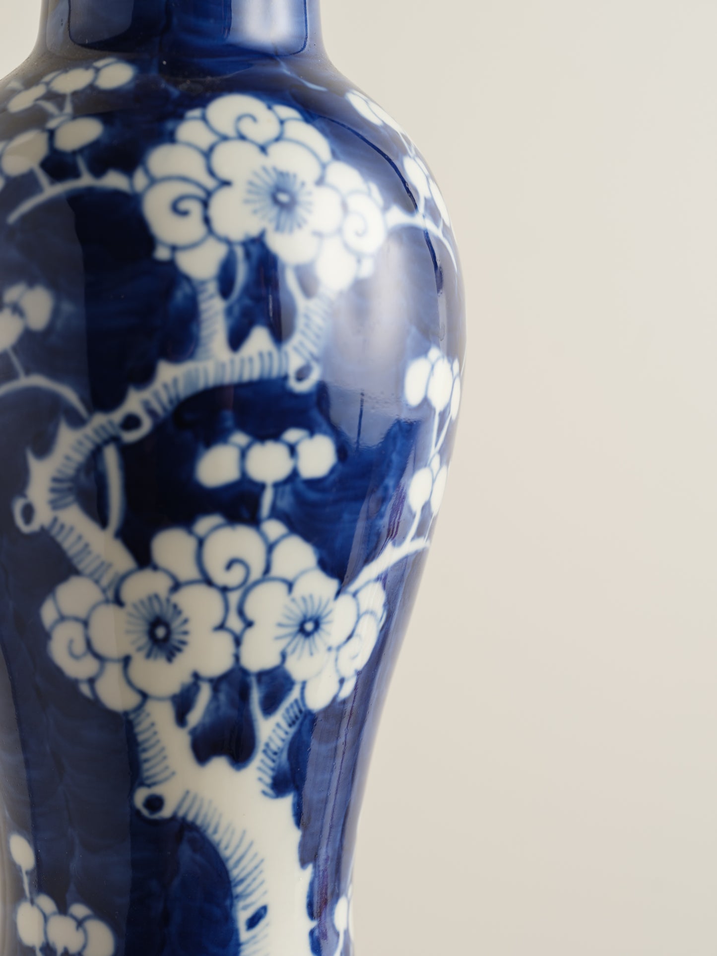 Porcelain vase in deep indigo glaze featuring hand-painted white plum blossoms.