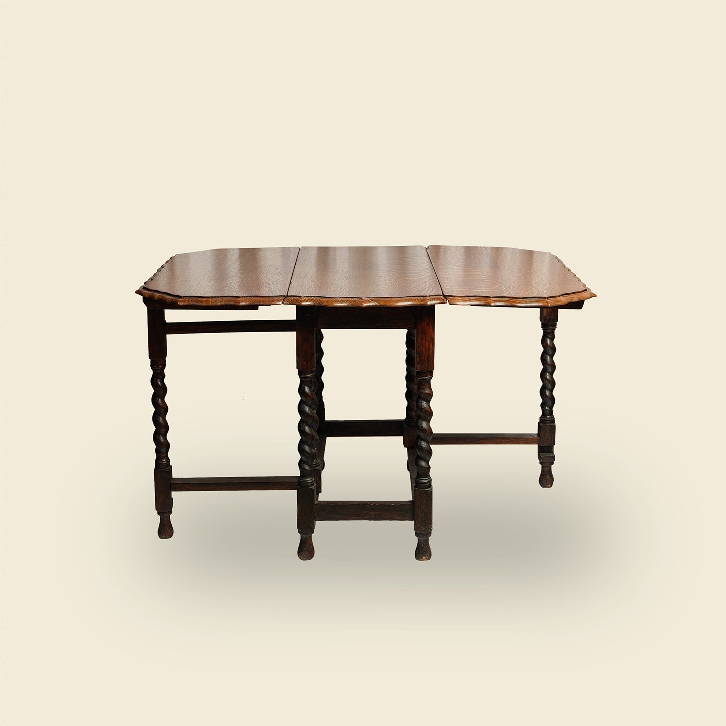 Antique oak gateleg dining table with barley twist legs, drop-leaf design against clear background