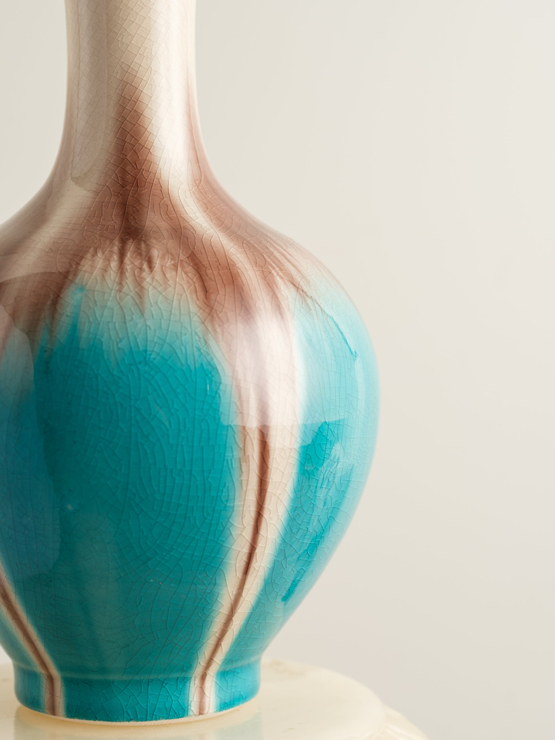 Ceramic vase with turquoise and beige drip glaze, featuring a flared neck and rounded form.