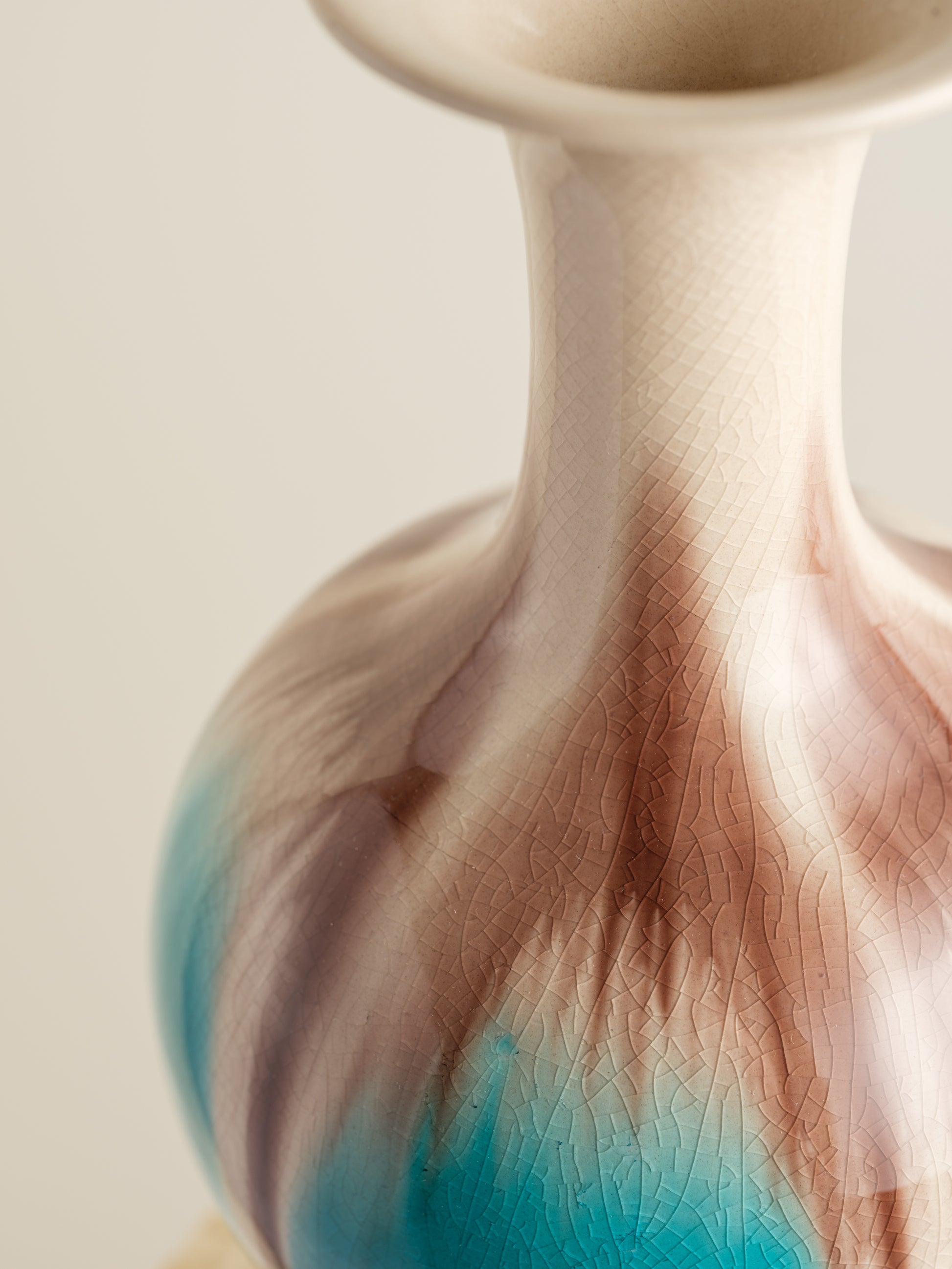 Ceramic vase with turquoise and beige drip glaze, featuring a flared neck and rounded form.