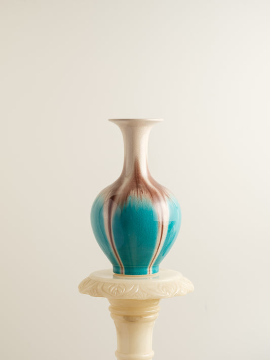 Ceramic vase with turquoise and beige drip glaze, featuring a flared neck and rounded form.