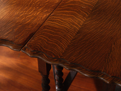 Antique oak gateleg dining table with barley twist legs, drop-leaf design against brick wall background