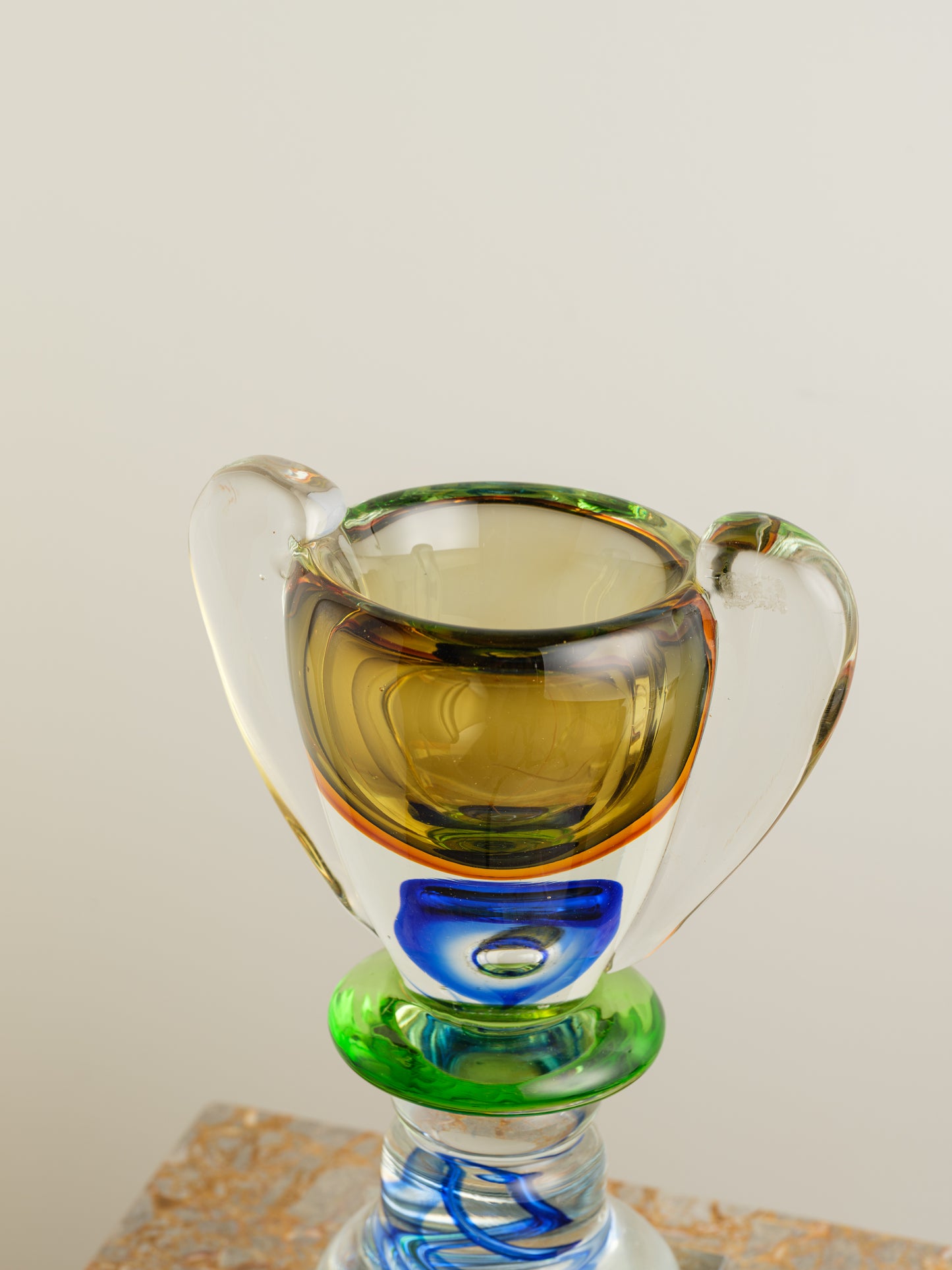 Multicoloured art glass vase with sculptural cup shape in yellow, green, blue and clear tones.