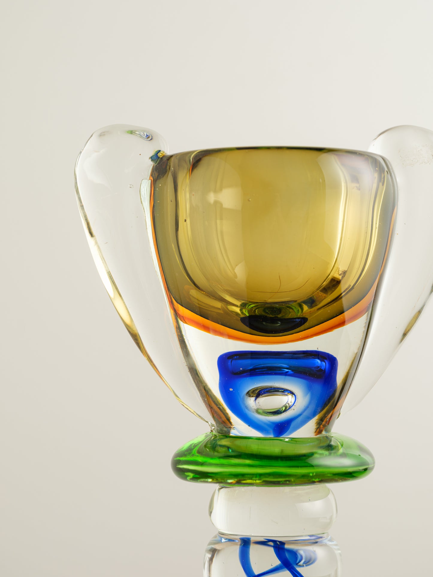 Multicoloured art glass vase with sculptural cup shape in yellow, green, blue and clear tones.