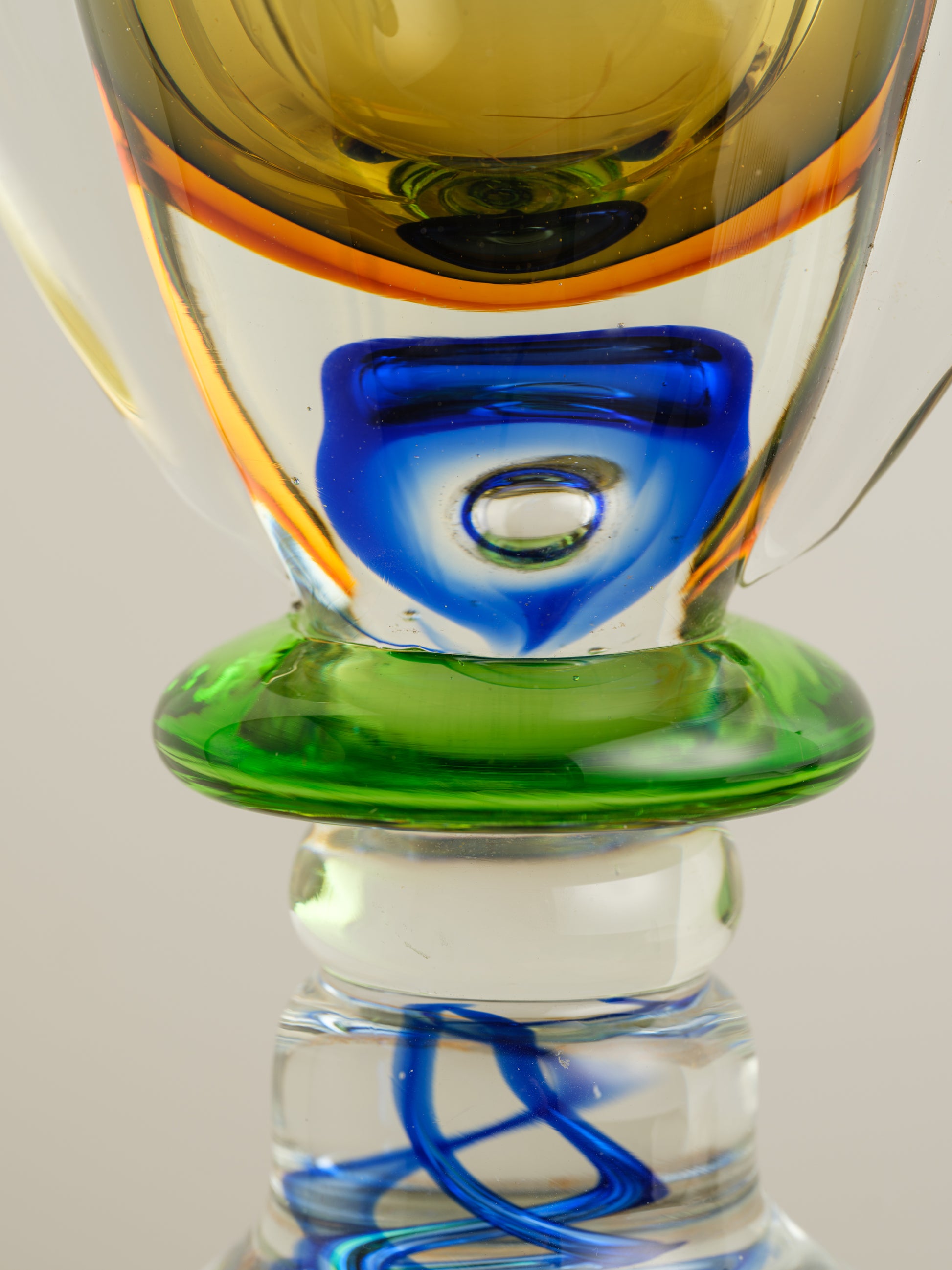 Multicoloured art glass vase with sculptural cup shape in yellow, green, blue and clear tones.