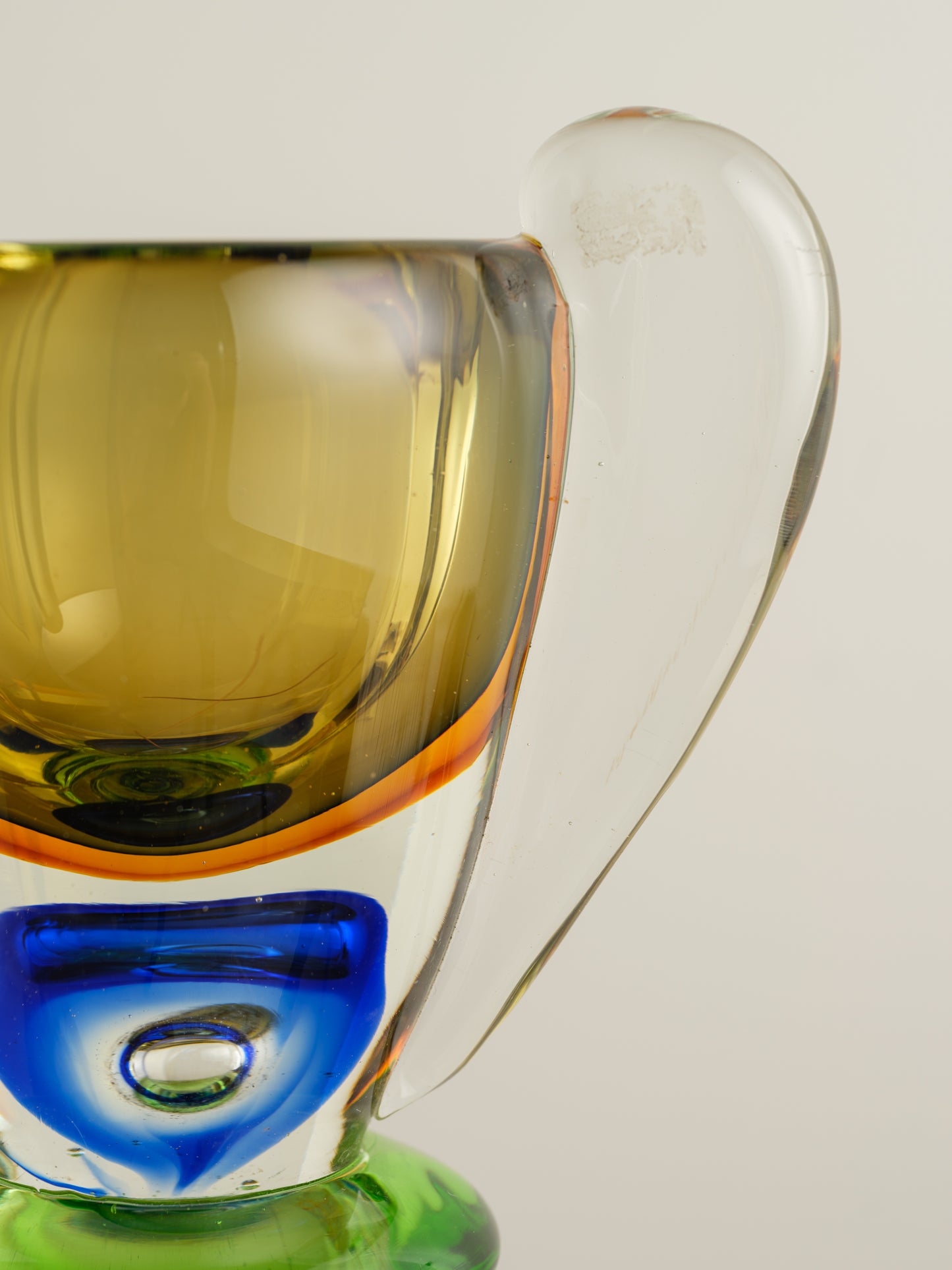 Multicoloured art glass vase with sculptural cup shape in yellow, green, blue and clear tones.