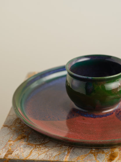 Hand-glazed ceramic bowl with matching charger in deep green and violet iridescent tones.