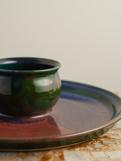 Hand-glazed ceramic bowl with matching charger in deep green and violet iridescent tones.