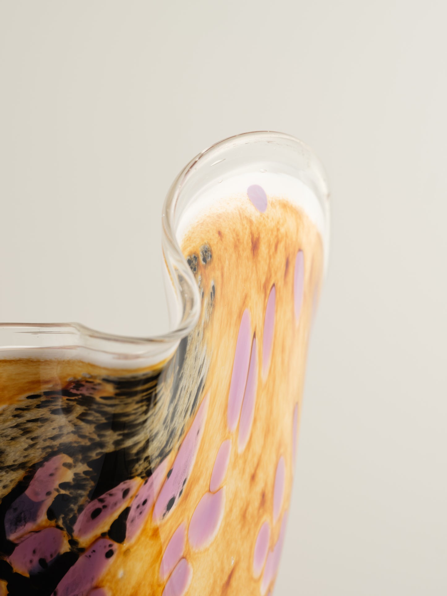 Handblown art glass vase with flowing petal form in shades of lilac, amber, and black.