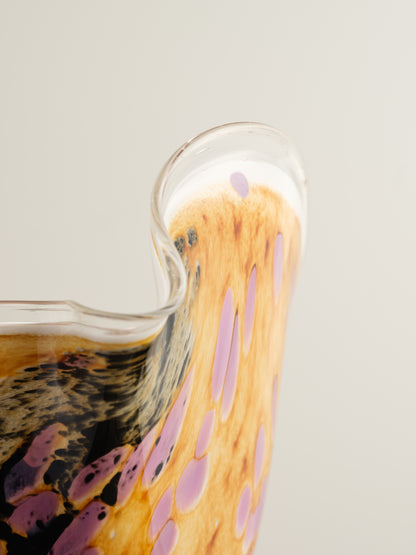 Handblown art glass vase with flowing petal form in shades of lilac, amber, and black.
