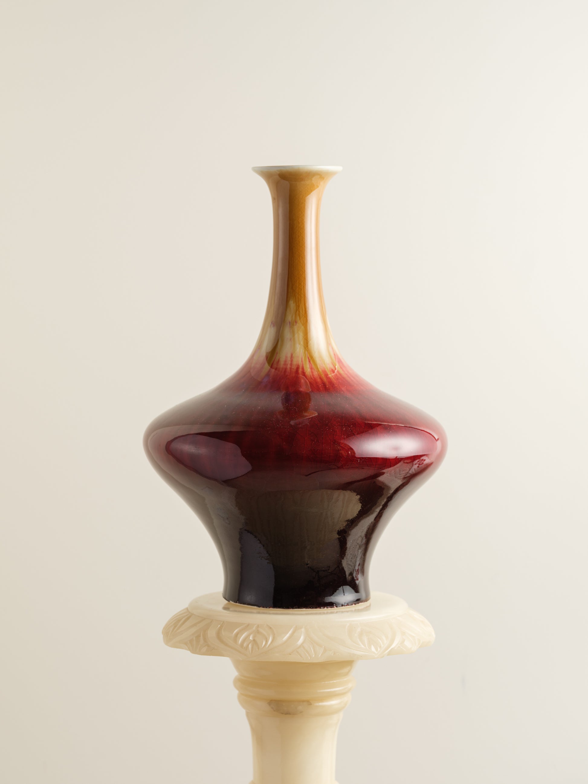 Flambé-glazed vase with a flared neck and rich gradient of crimson, amber, and deep oxblood hues.