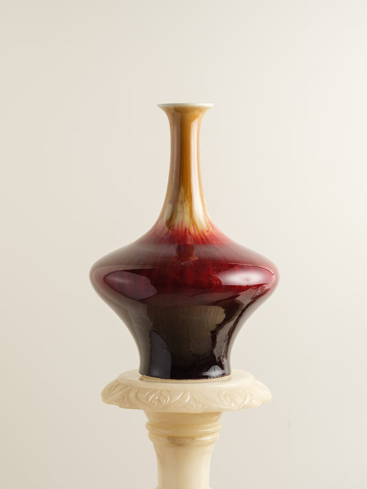 Flambé-glazed vase with a flared neck and rich gradient of crimson, amber, and deep oxblood hues.