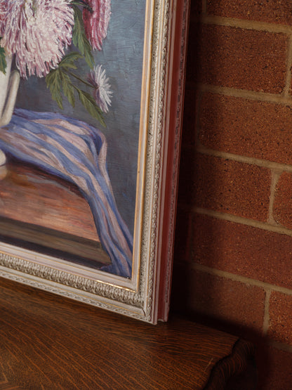 Oil painting titled Blush Chrysanthemums in White Vase, featuring a lush bouquet of pink chrysanthemums arranged in a classic white vase with a striped blue cloth.