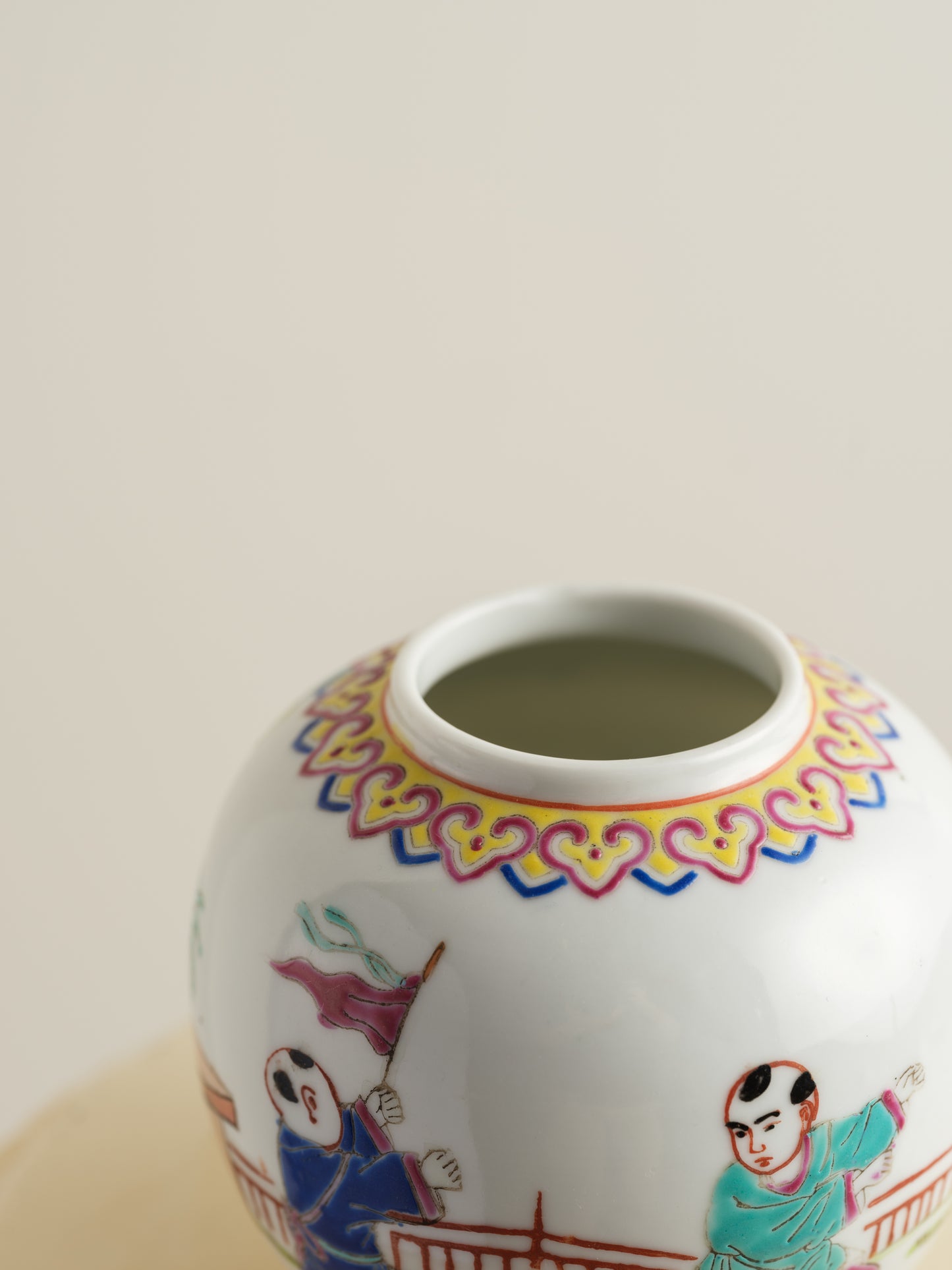 Small porcelain jar hand-painted with playful courtyard children in bright traditional robes.