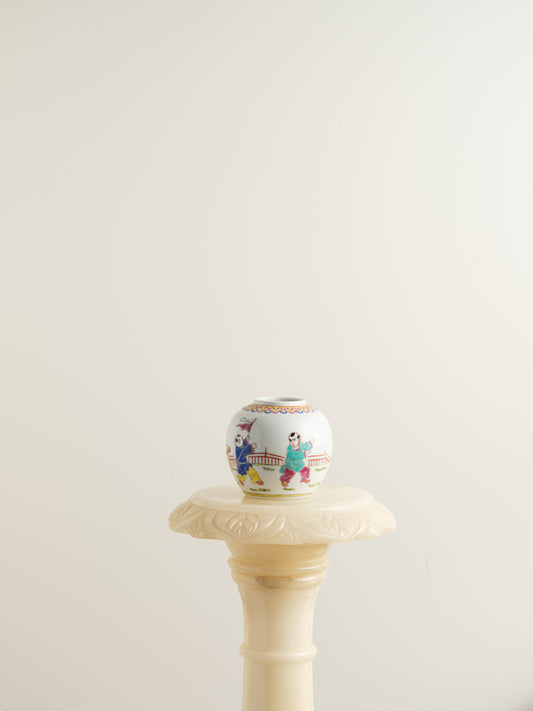 Small porcelain jar hand-painted with playful courtyard children in bright traditional robes.