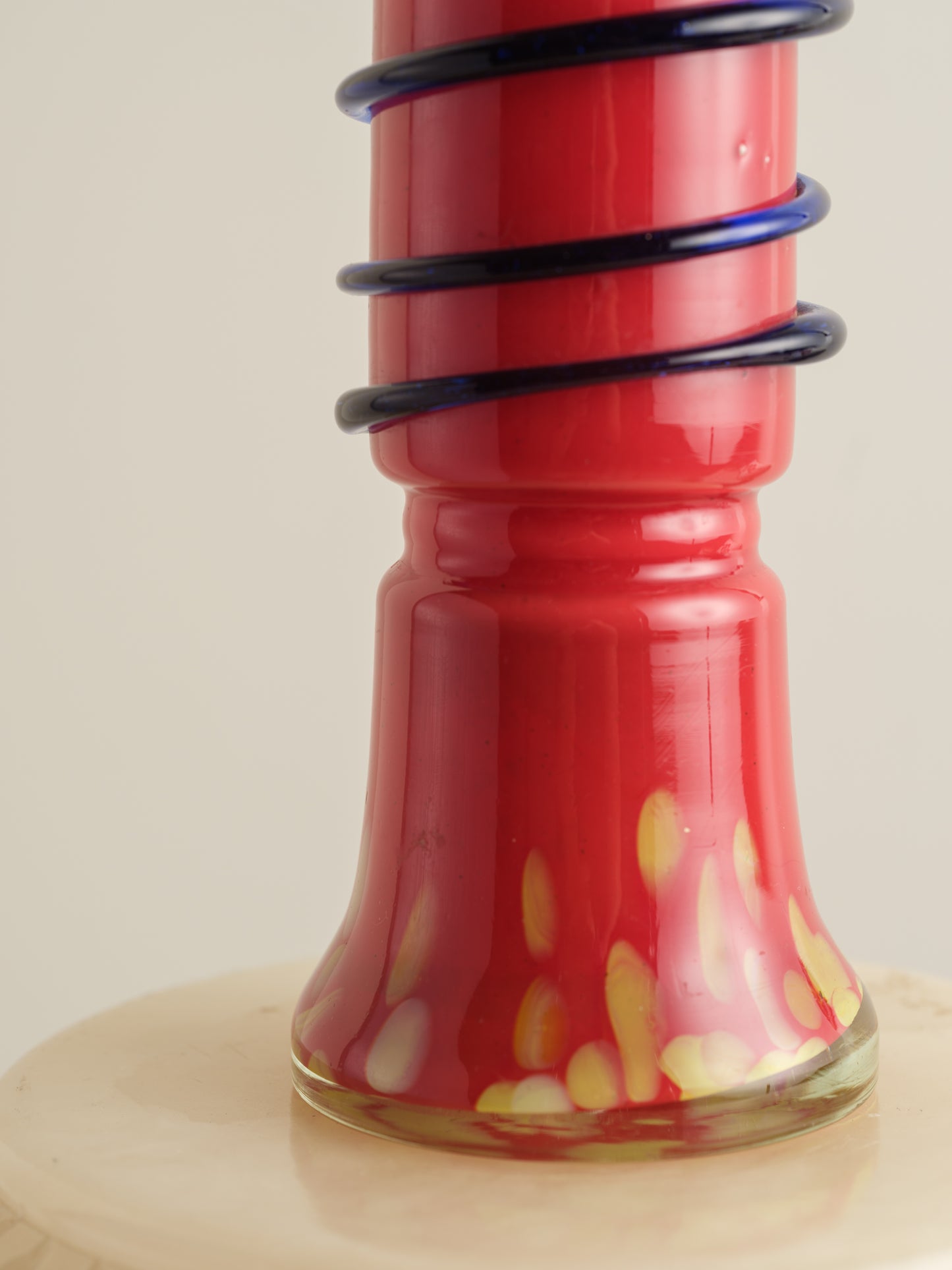 Red glass bud vase with flared rim and cobalt spiral accent wrapping around the neck.
