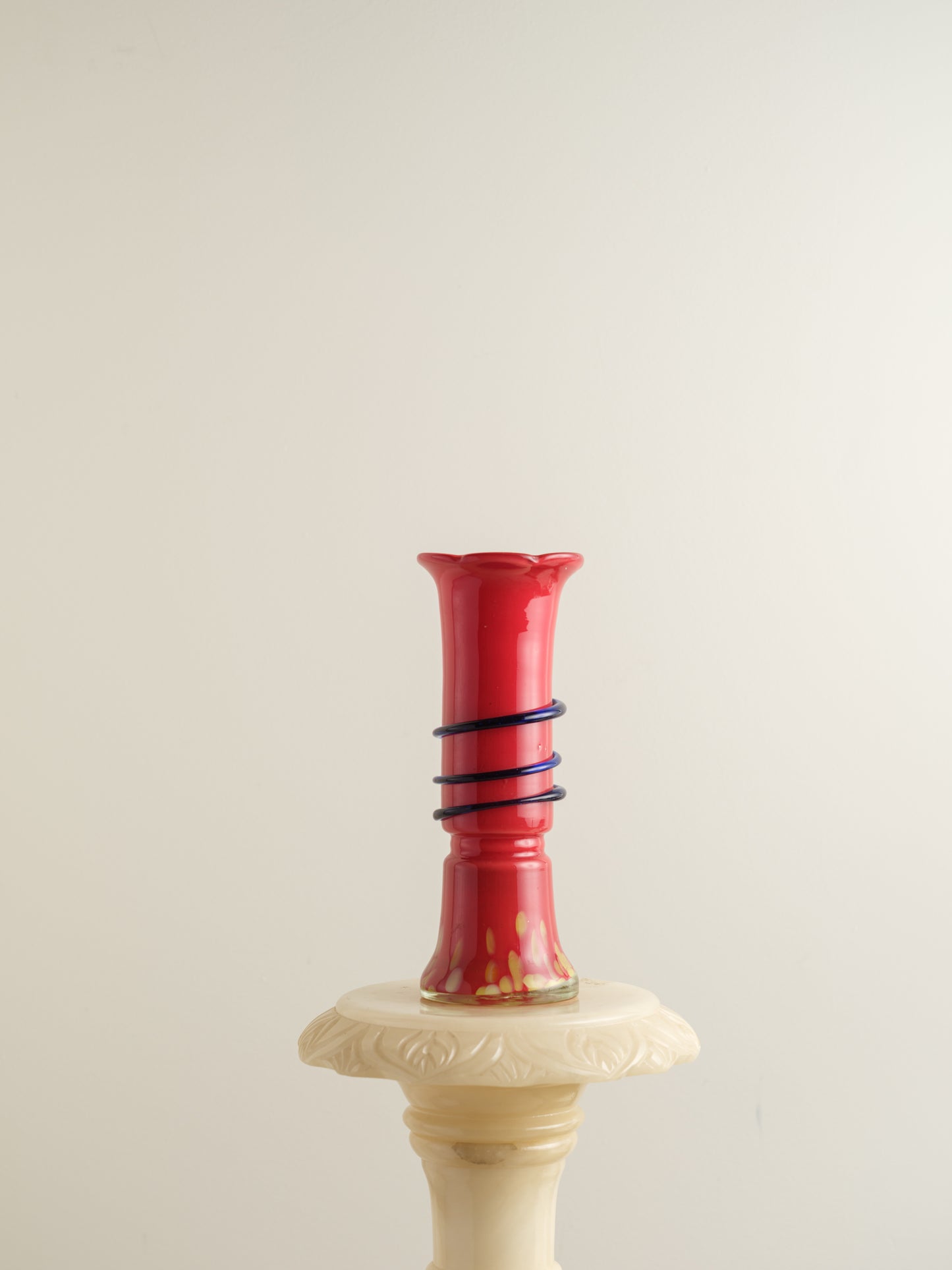 Red glass bud vase with flared rim and cobalt spiral accent wrapping around the neck.
