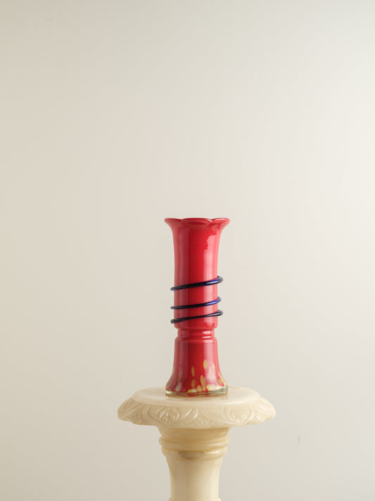 Red glass bud vase with flared rim and cobalt spiral accent wrapping around the neck.
