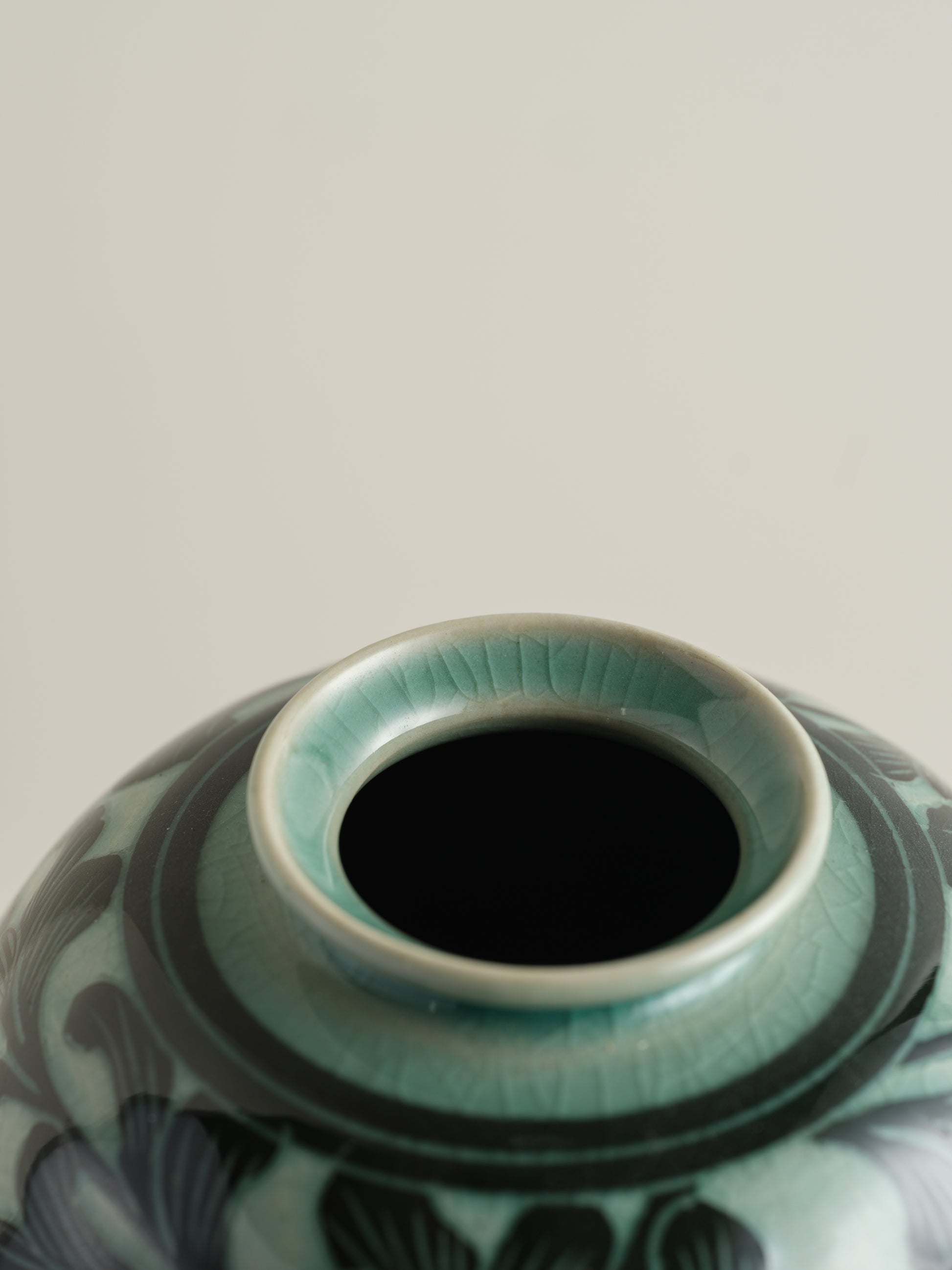 Hand-painted ceramic jar in deep green tones with scrolling leaf and floral patterns.
