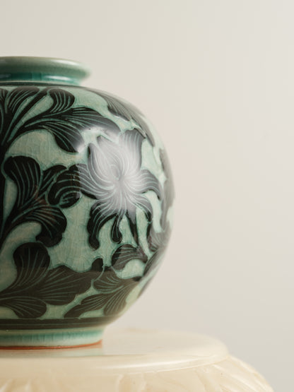 Hand-painted ceramic jar in deep green tones with scrolling leaf and floral patterns.