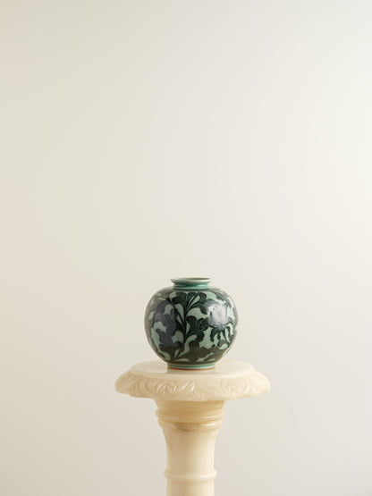 Hand-painted ceramic jar in deep green tones with scrolling leaf and floral patterns.