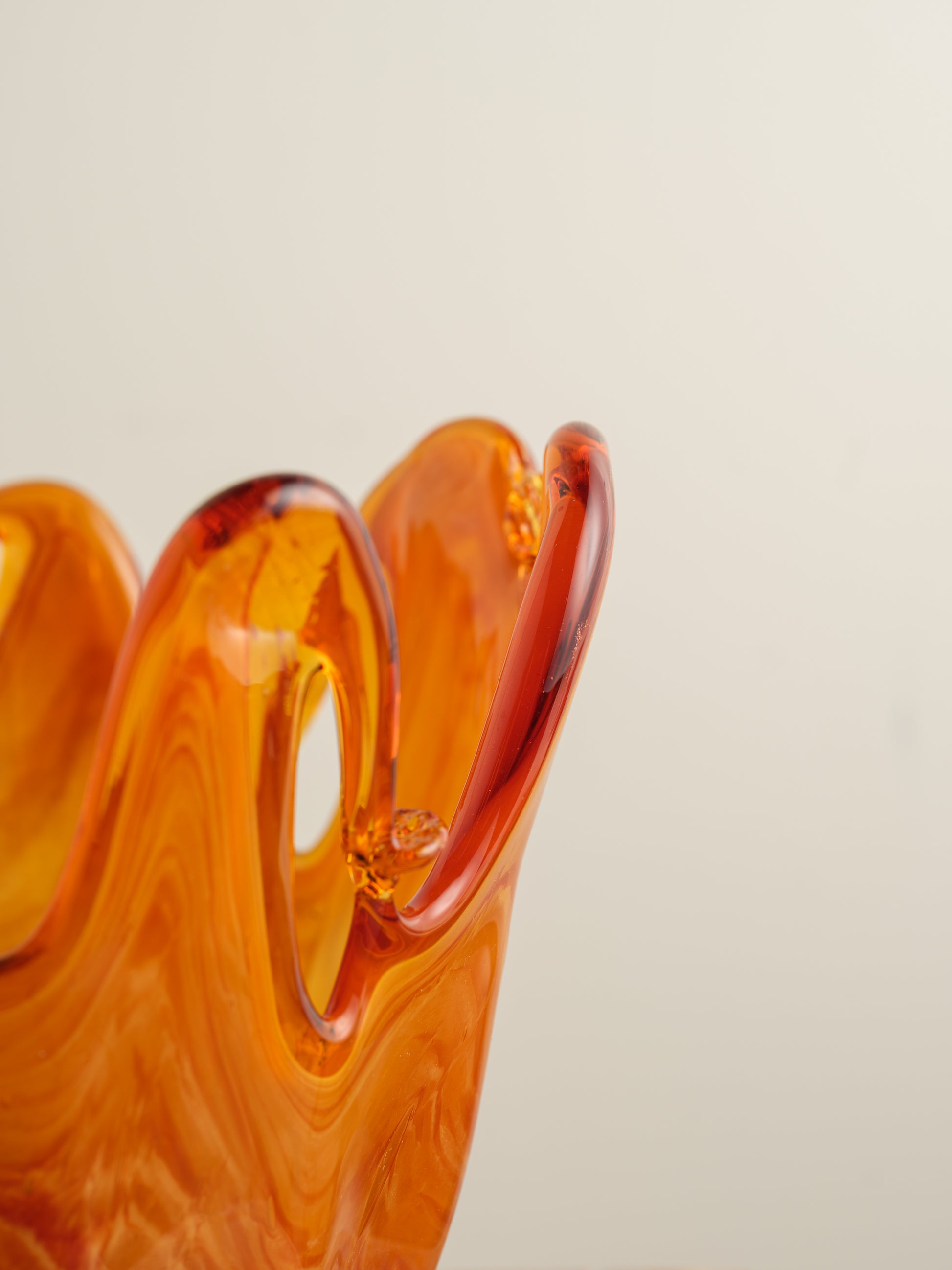 Handblown orange glass bowl with fluid wavy rim and marbled amber tones.
