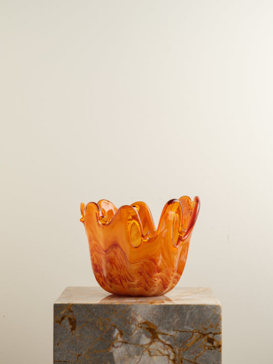 Handblown orange glass bowl with fluid wavy rim and marbled amber tones.