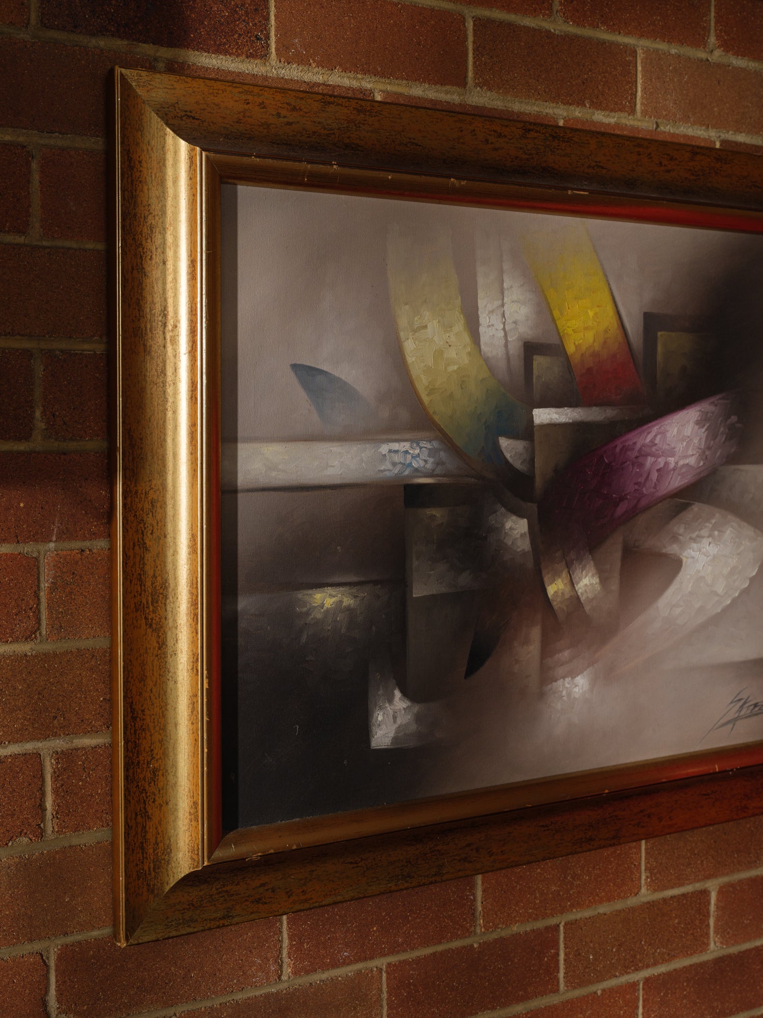 Oil painting titled Gilded Ribbons, featuring sweeping abstract curves in gold, crimson, and muted tones, layered over a smoky brown and grey background, framed in gold.