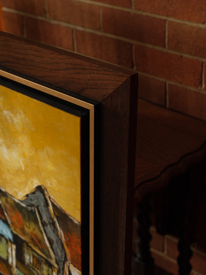 Oil painting titled Golden Eaves on Old Street, depicting a row of traditional houses with weathered tiled roofs under a golden-yellow sky, framed in dark wood.