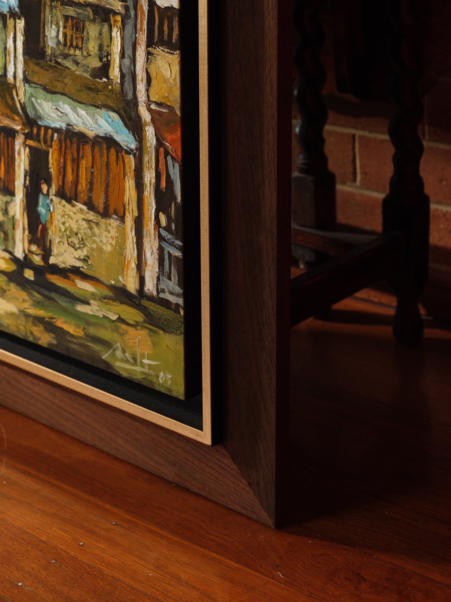 Oil painting titled Golden Eaves on Old Street, depicting a row of traditional houses with weathered tiled roofs under a golden-yellow sky, framed in dark wood.
