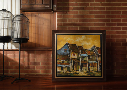 Oil painting titled Golden Eaves on Old Street, depicting a row of traditional houses with weathered tiled roofs under a golden-yellow sky, framed in dark wood.