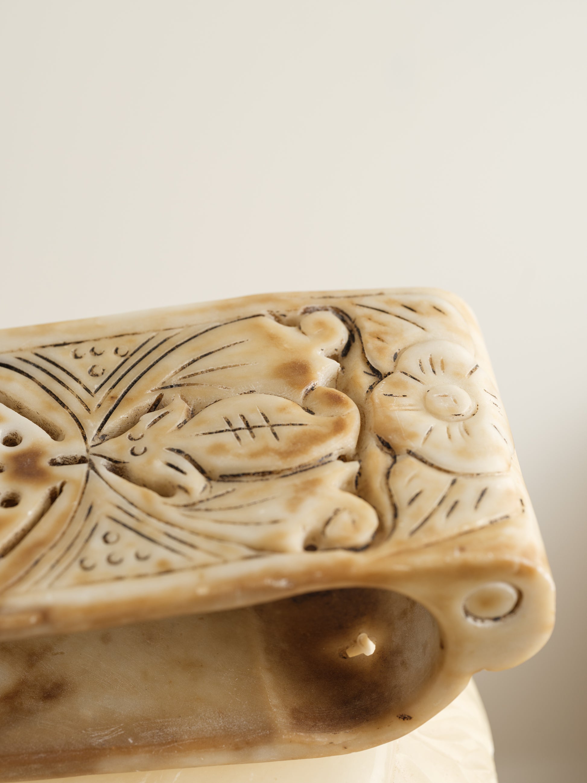 Ivory-toned pedestal stand with curved top and carved detailing, ideal for displaying vases or sculptures.