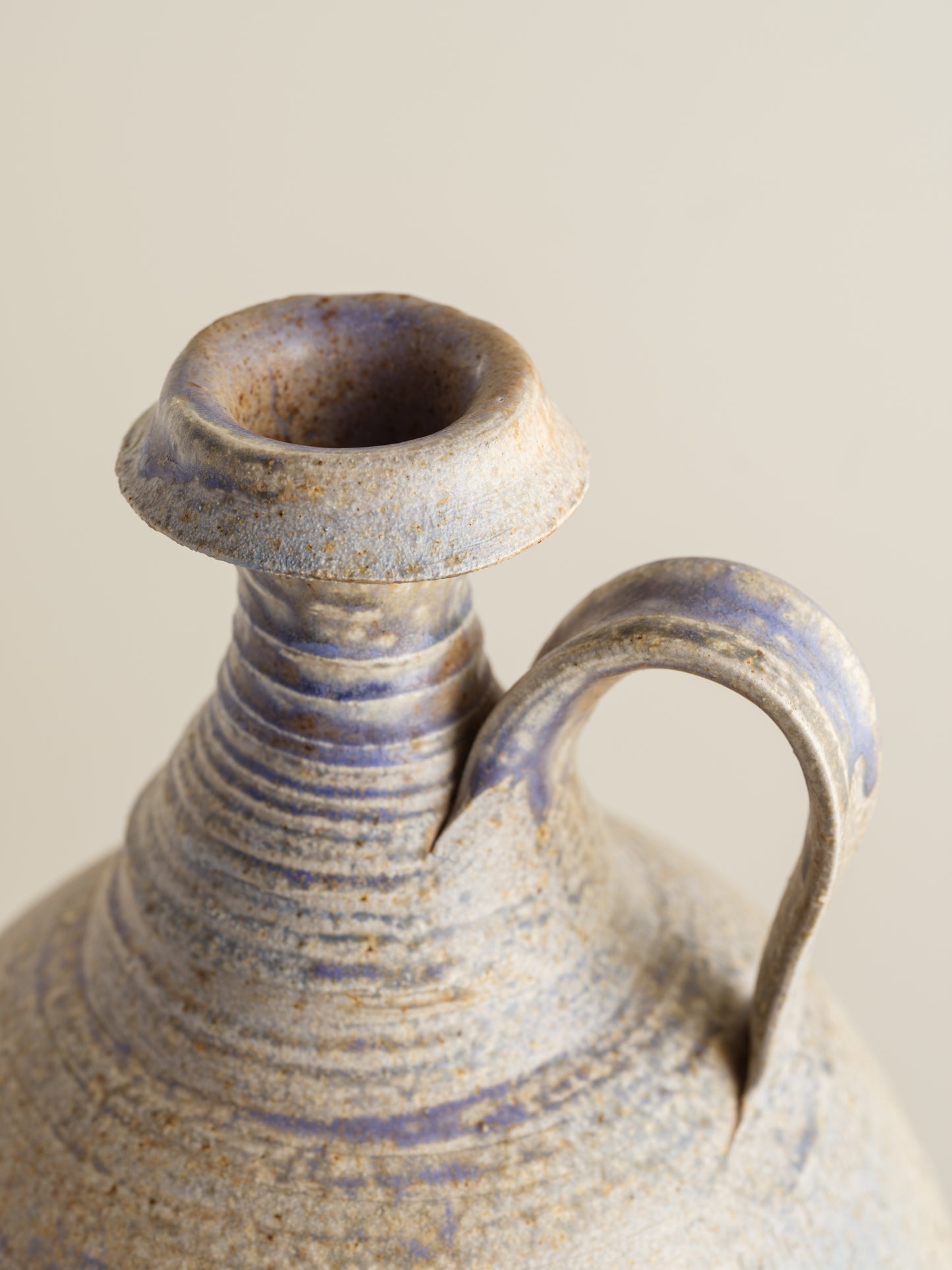 Hand-thrown stoneware ewer with lavender and sand-toned glaze and textured surface.