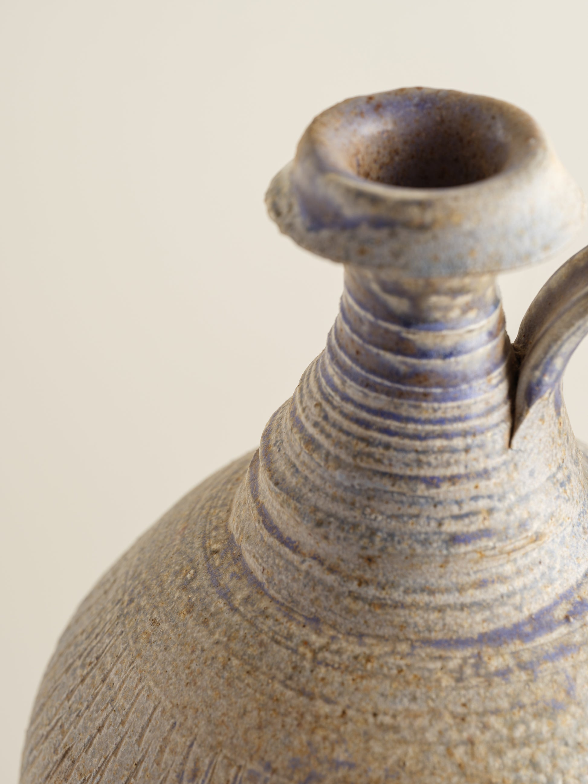 Hand-thrown stoneware ewer with lavender and sand-toned glaze and textured surface.