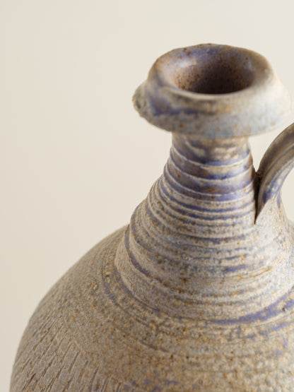 Hand-thrown stoneware ewer with lavender and sand-toned glaze and textured surface.