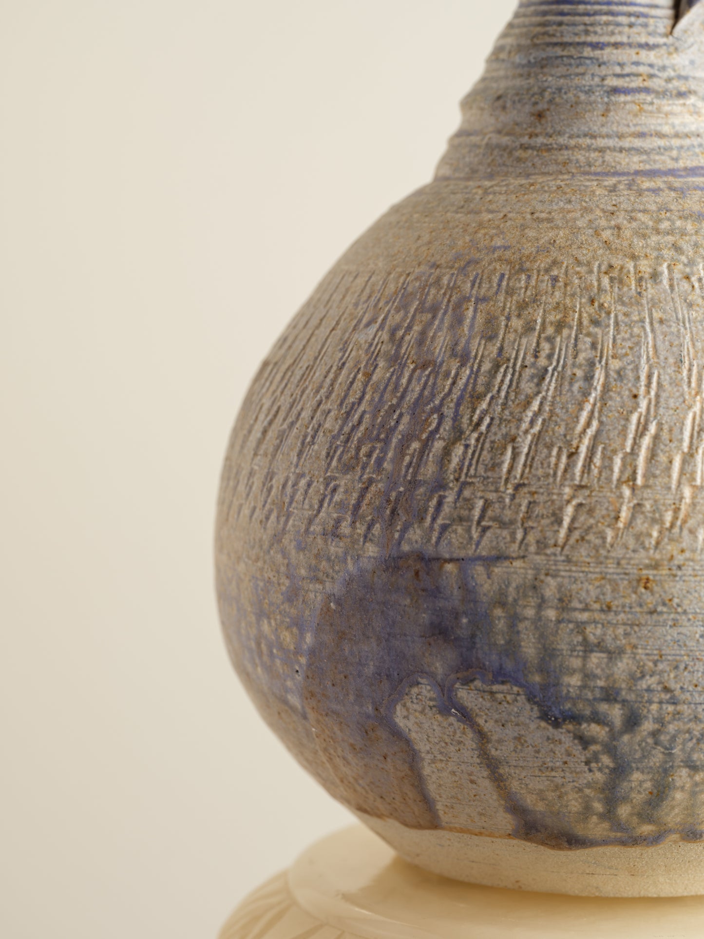 Hand-thrown stoneware ewer with lavender and sand-toned glaze and textured surface.