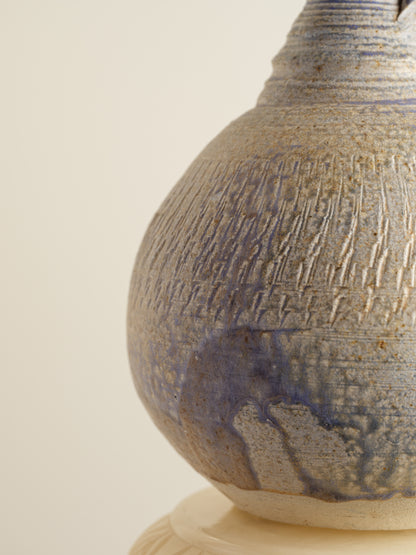Hand-thrown stoneware ewer with lavender and sand-toned glaze and textured surface.
