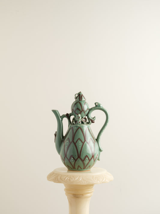 Celadon ewer with lotus petal relief design and sculpted handle and spout, finished in green glaze with brown accents.