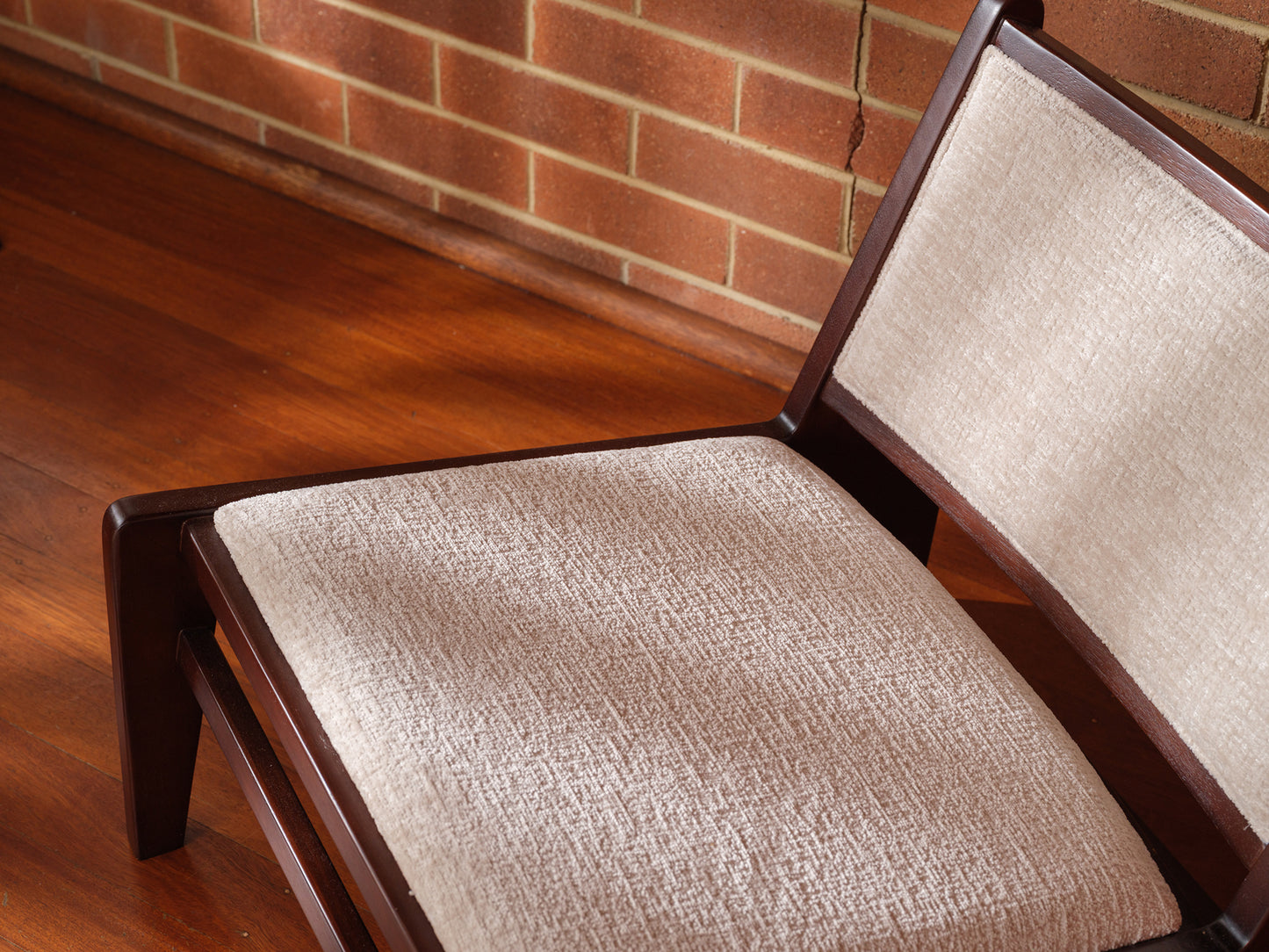 Low armchair with dark brown wooden frame and beige fabric upholstery, modern vintage design