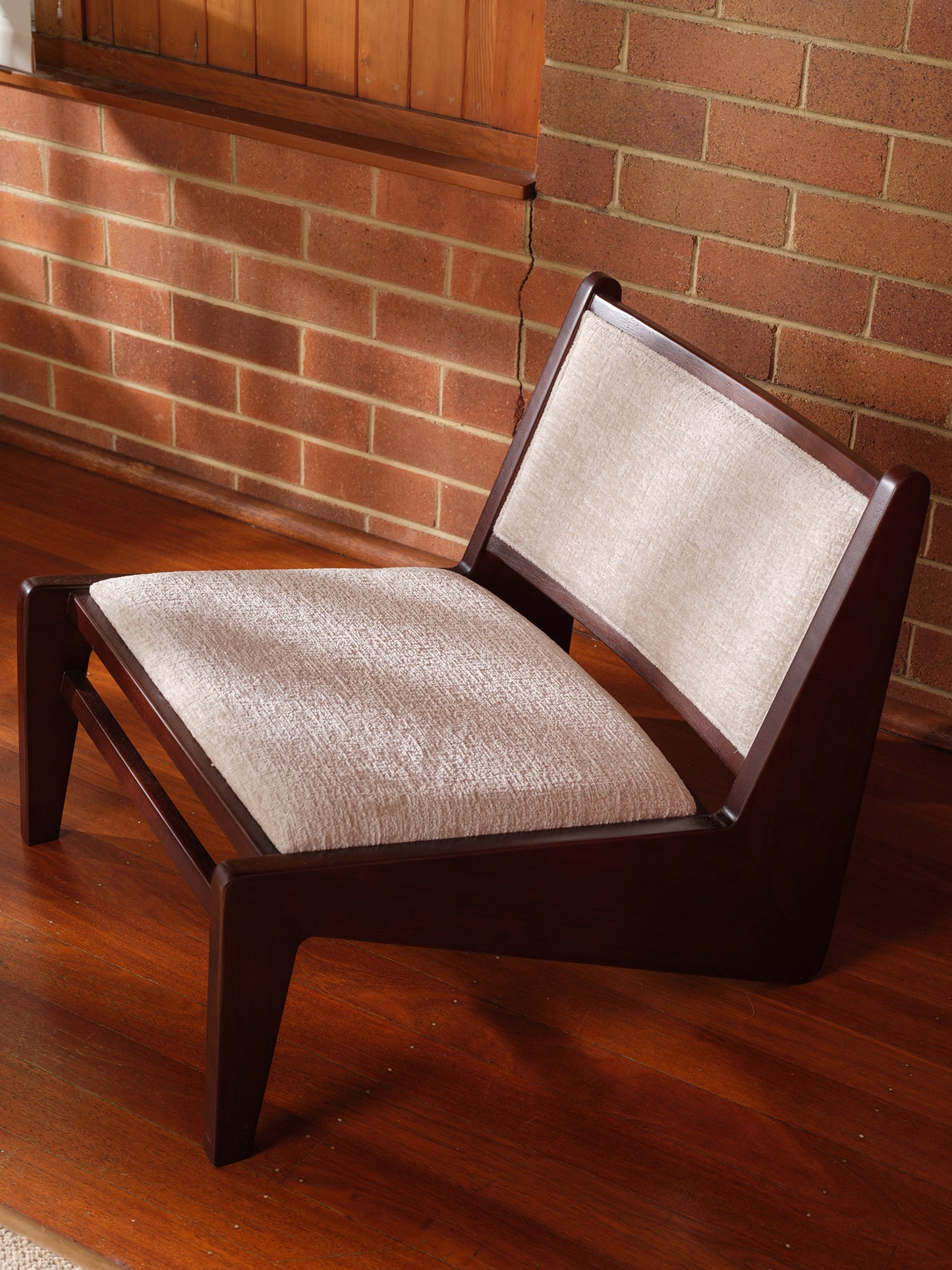 Low armchair with dark brown wooden frame and beige fabric upholstery, modern vintage design