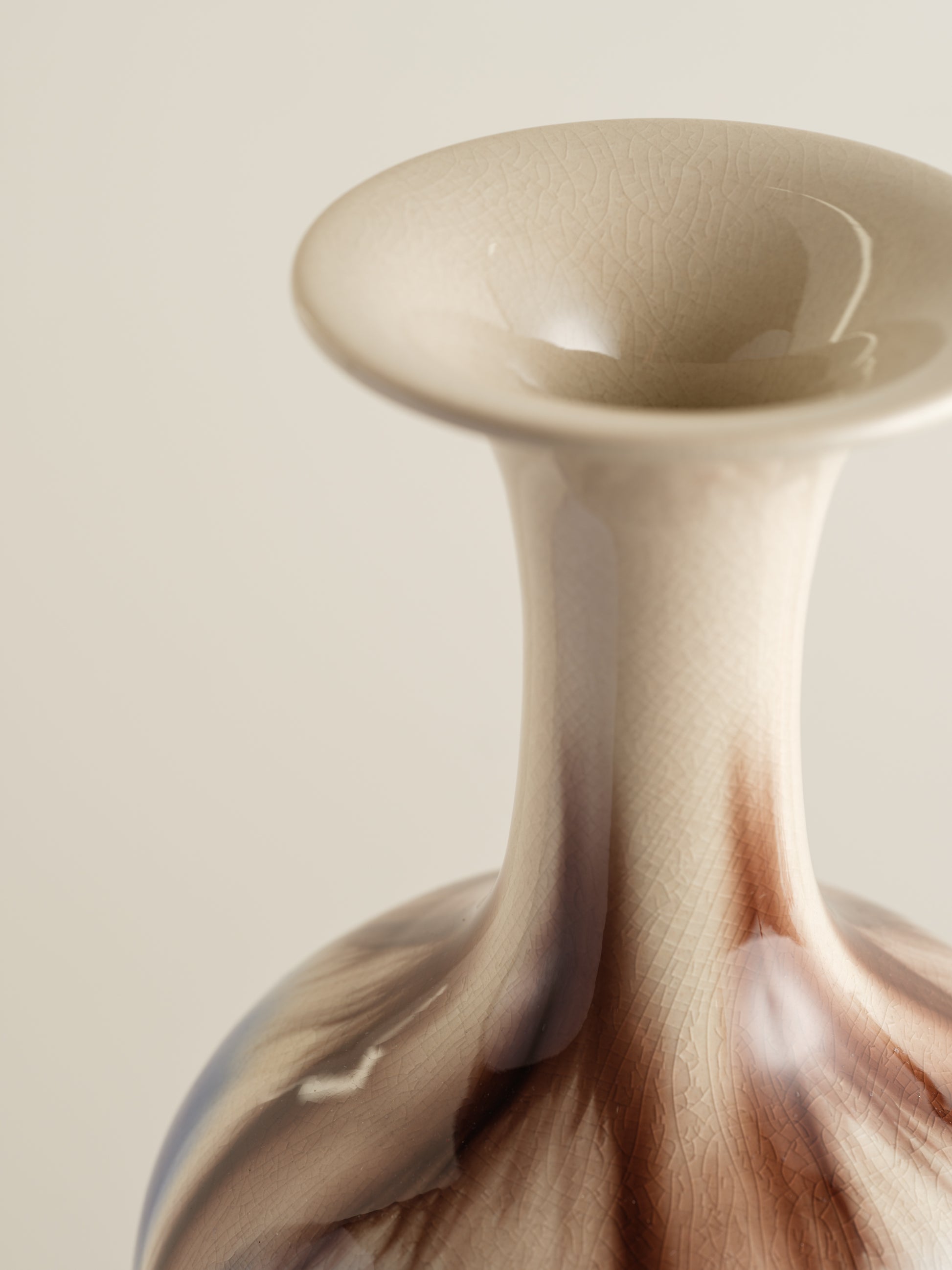 Porcelain vase with flowing drip-glaze in indigo, cream, and russet tones.