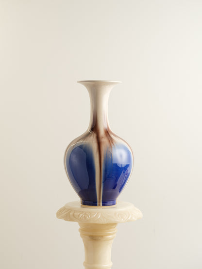 Porcelain vase with flowing drip-glaze in indigo, cream, and russet tones.