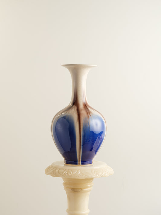 Porcelain vase with flowing drip-glaze in indigo, cream, and russet tones.