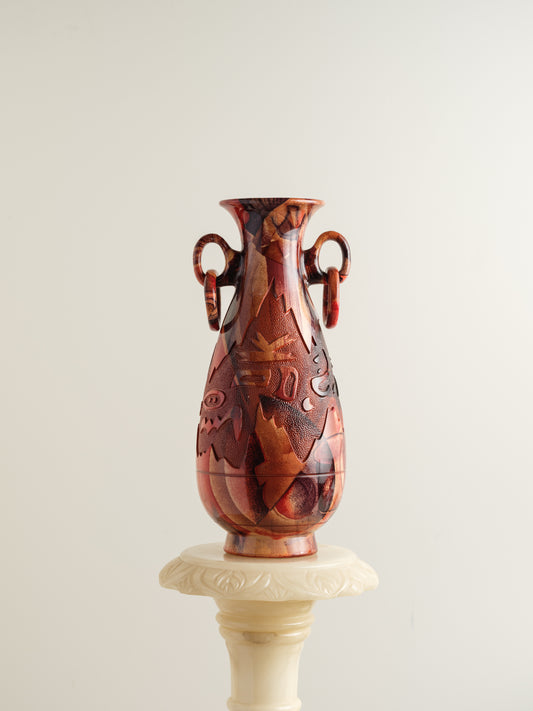 Decorative ceramic vase with red ochre glaze, featuring intricate carved motifs and twin ring handles.