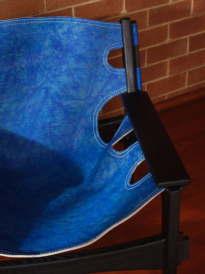 Replica Sergio Rodrigues Kilin lounge chair in blue leather with black wooden frame with brick wall