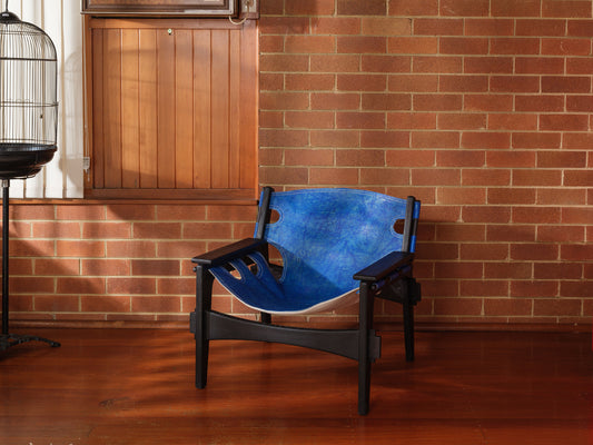 Replica Sergio Rodrigues Kilin lounge chair in blue leather with black wooden frame with brick wall