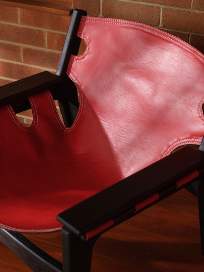 Replica Sergio Rodrigues Kilin lounge chair in red leather with black wooden frame with brick wall background