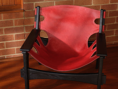 Replica Sergio Rodrigues Kilin lounge chair in red leather with black wooden frame with brick wall background